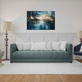 A canvas painting displayed above a green sofa with white cushions, featuring an abstract design with blue and gold colors.