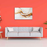 A canvas painting featuring an abstract white and golden texture, displayed above a gray sofa on a red wall.