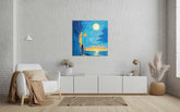A canvas painting depicting a woman walking on a sidewalk at dusk or dawn with a focus on the moon, displayed on a wall in a modern living room setting.