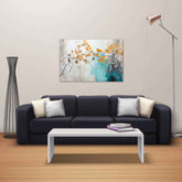 A canvas print featuring an abstract painting of flowers displayed above a black sofa with white and beige pillows, placed in a room with a white table, a floor lamp, and a decorative object.