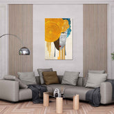 A modern abstract geometric painting displayed on a wall above a gray sofa with a contemporary design featuring predominantly yellow and blue colors.