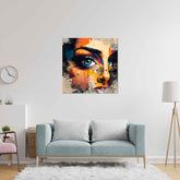 A modern abstract painting of a woman's face displayed on a canvas, hung above a gray sofa in a room with minimalist decor.