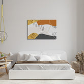 A canvas print featuring geometric shapes in beige, gray, black, and gold colors, displayed above a bed in a room with a minimalist decor.