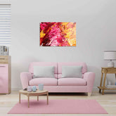 A canvas oil painting displayed above a pink sofa in a room with a light interior, featuring abstract red and yellow colors.