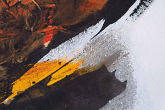 A canvas print featuring an abstract painting with black, white, and yellow hues, displayed above a desk with a laptop and a vase with dried flowers.
