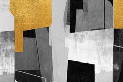 A canvas print featuring abstract geometric shapes in black, white, gray, and yellow, displayed above a grey sofa with a plant to the left.