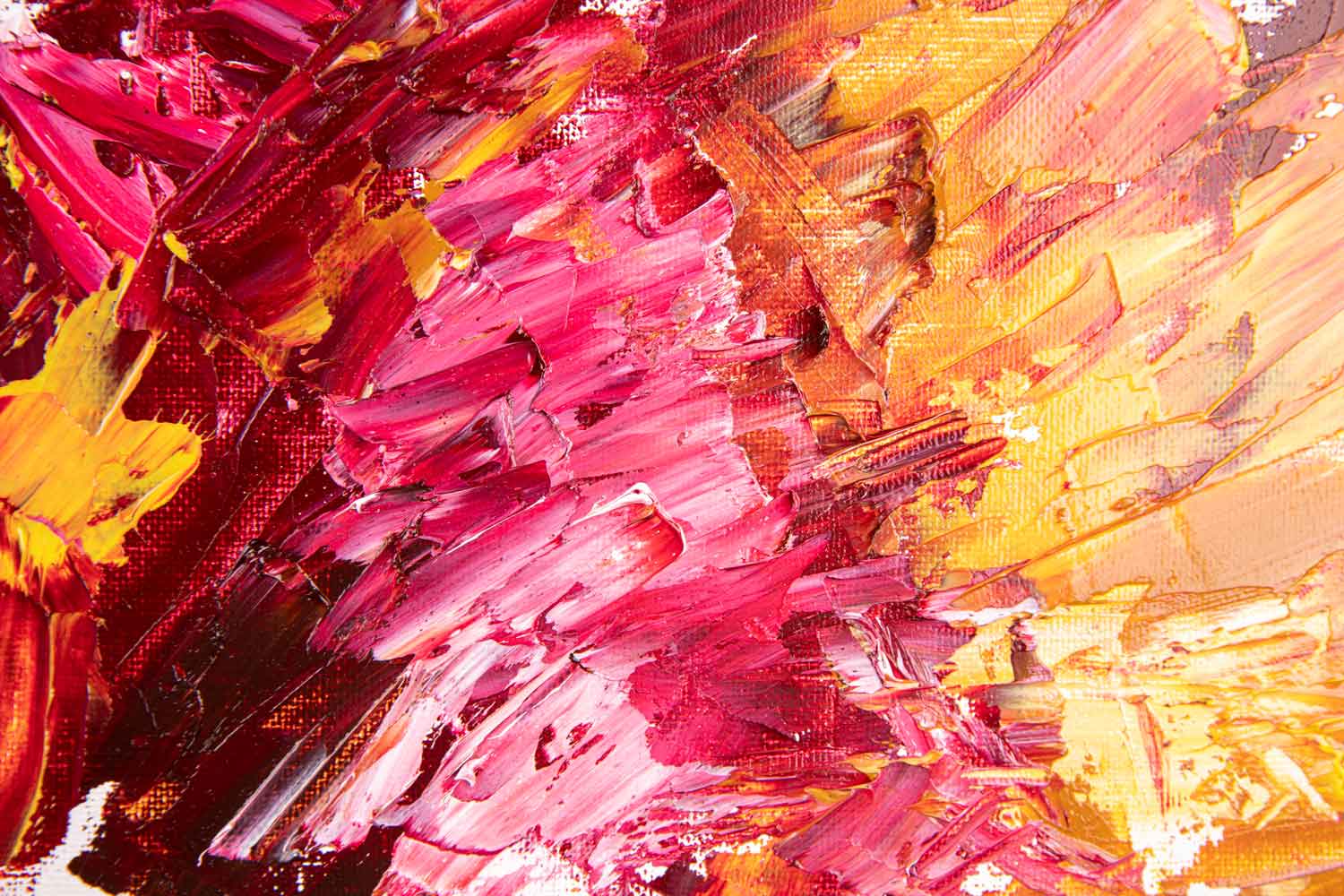 A canvas oil painting displayed above a pink sofa in a room with a light interior, featuring abstract red and yellow colors.