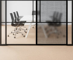 Modern office setup with glass walls, chairs, and a desk.