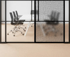 Modern office interior with glass walls, black chairs, and a textured wall.