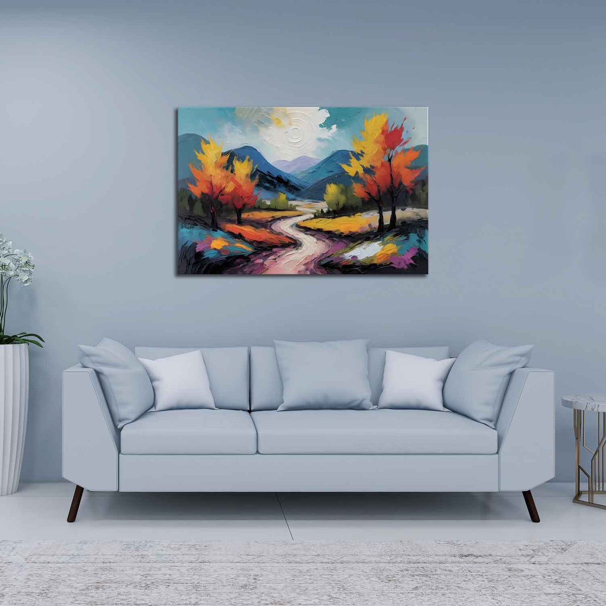 A canvas print featuring a vibrant painting with a winding road, trees, and a mountain range in the background, displayed above a gray sofa in a room with a light blue wall.