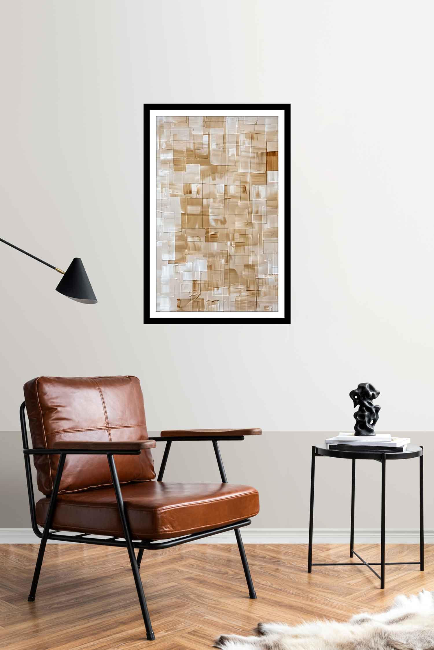 A geometric square shape canvas print hanging on a wall over a white chair and wooden floor, with a framed picture to the side and a lamp above the chair.