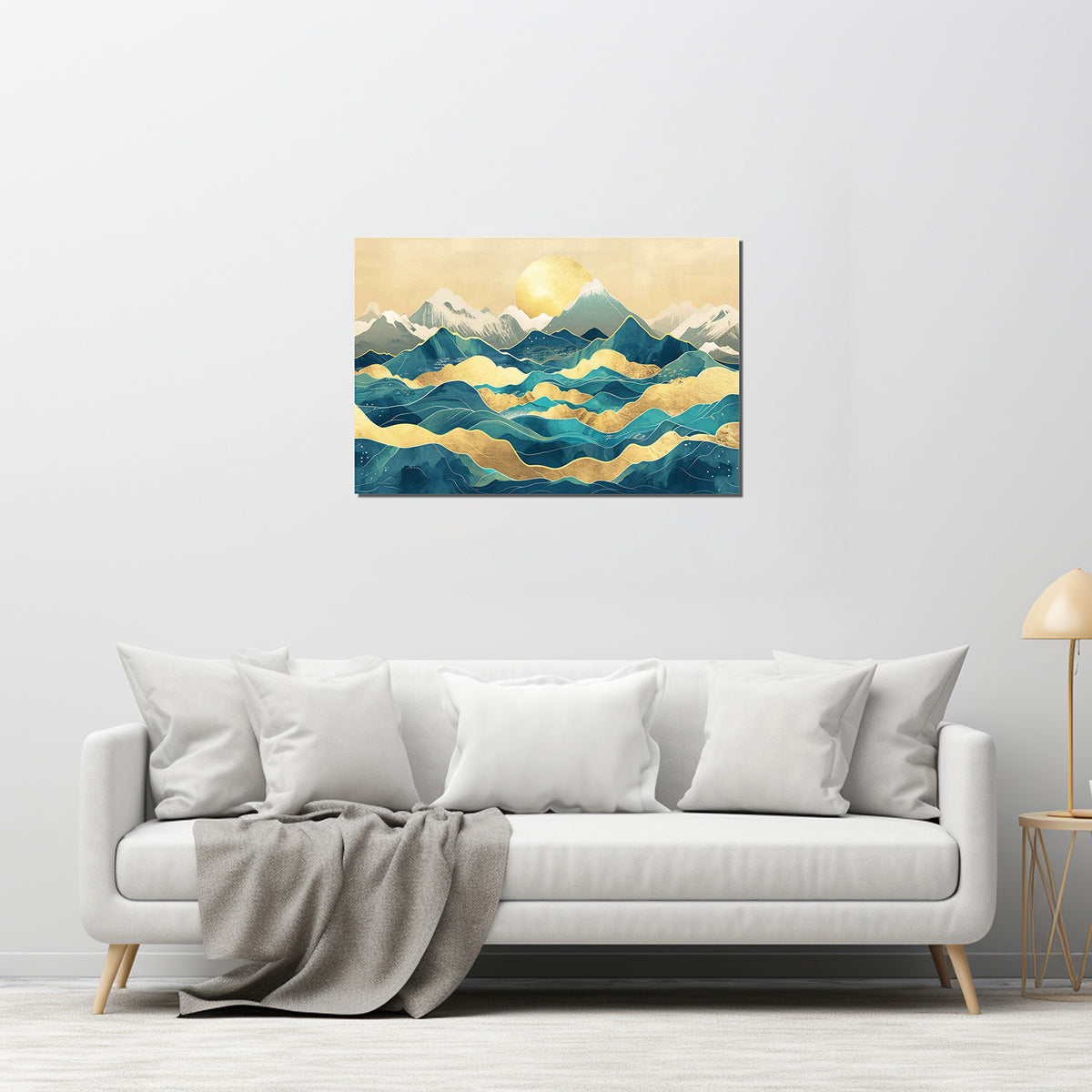 A canvas print featuring a mountainous landscape with a golden line in the sky, displayed on a wall above a white sofa with grey pillows.